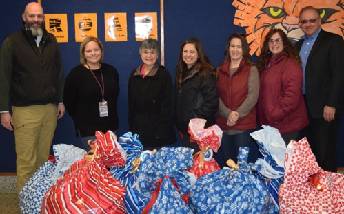F&M Trust employees and school officials stand with bags of coat donations