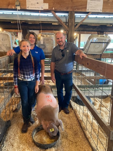 Bank reps standing with Makena and her pig