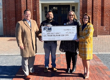 Image of three F&M Trust employees presenting a check to a representative of the Broad Street Market.