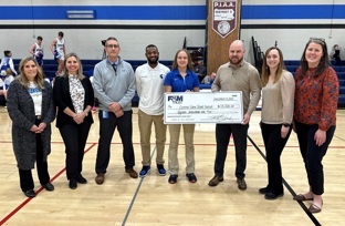 F&M Trust employees and CFSD employees posing with a large check in the gymnasium.